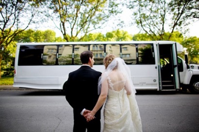 bride and groom standing infront of wedding party bus